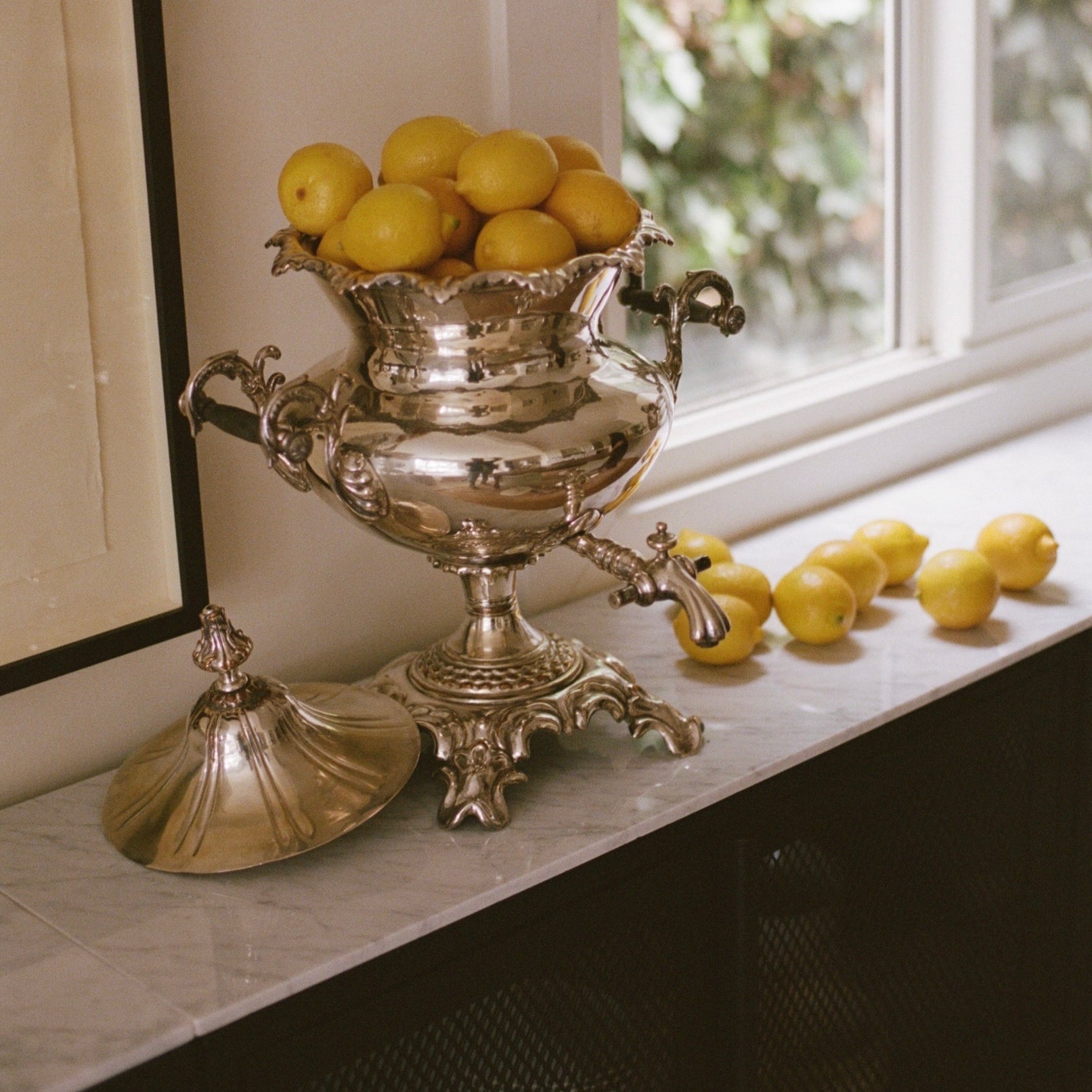 Decorative silver urn with lemons on a windowsill