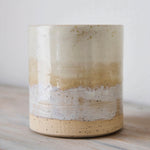 Ceramic cup with layered beige and white design on a wooden surface