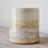 Ceramic cup with layered beige and white design on a wooden surface