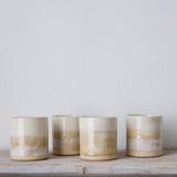 Four ceramic jars with a gradient finish on a wooden surface against a light background