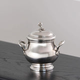 Silver sugar bowl with lid on a dark surface
