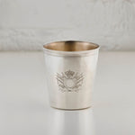 Silver cup with engraved design on a light gray background
