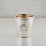 Silver cup with engraved design on a light gray background