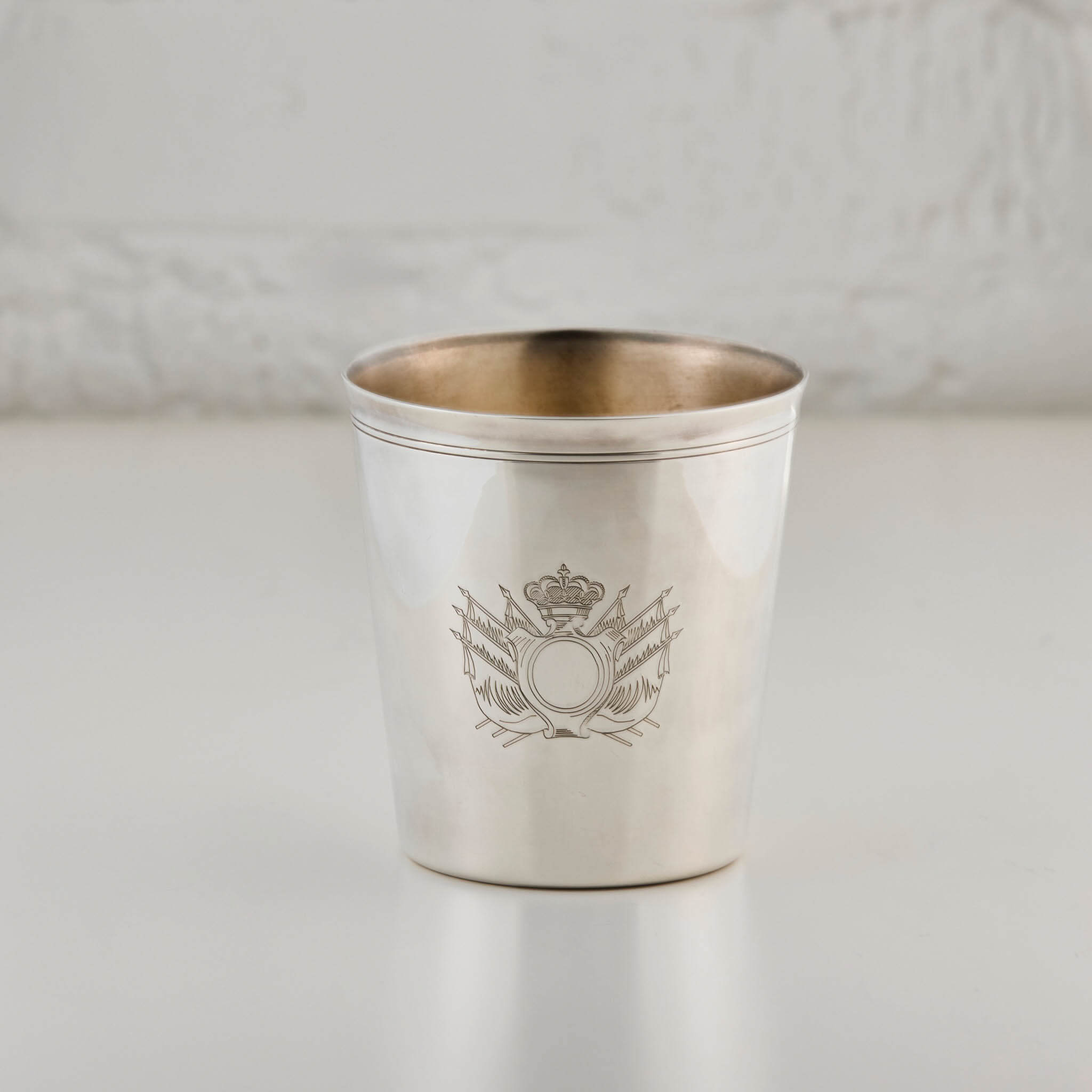 Silver cup with engraved design on a light gray background