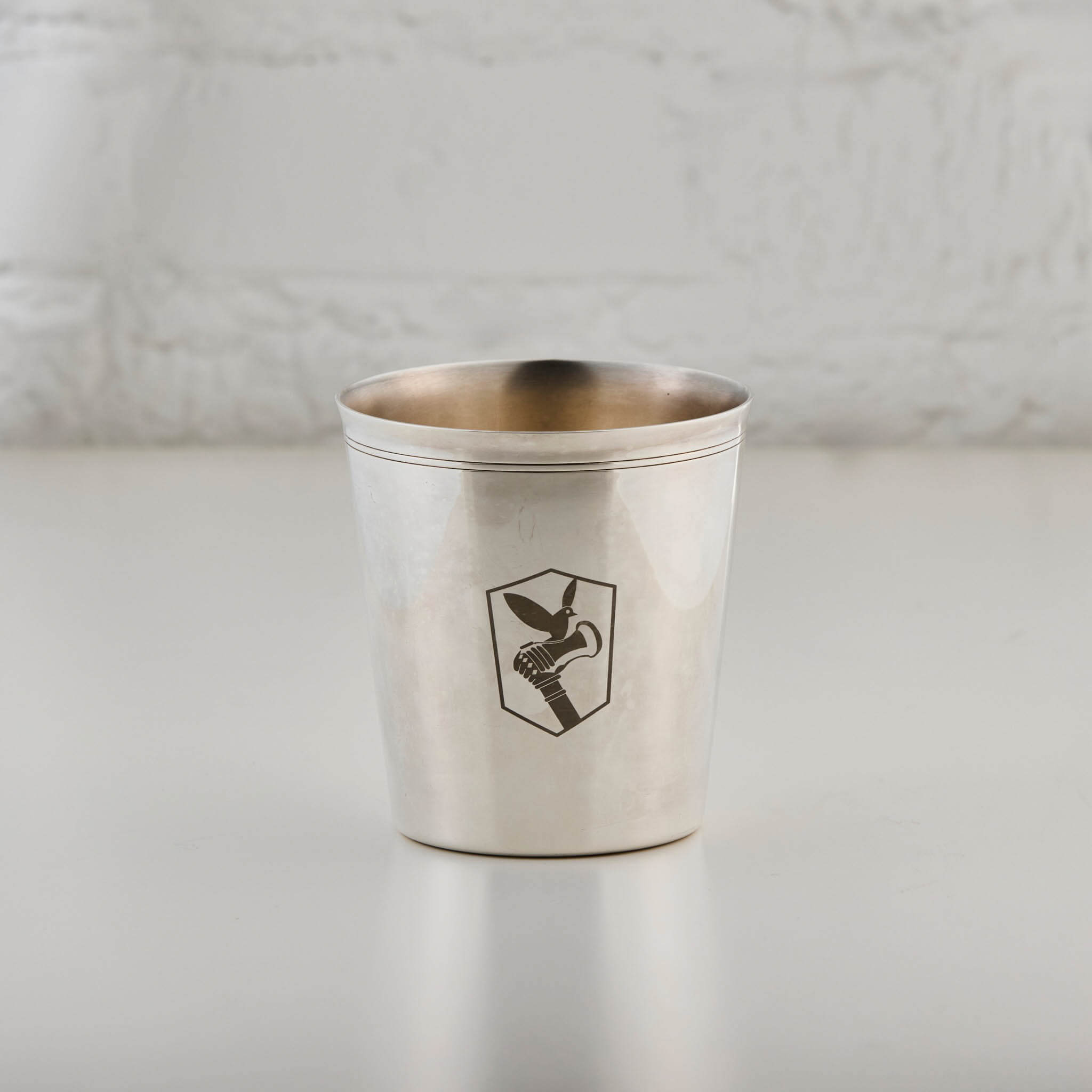Silver cup with an engraved logo on a light gray background
