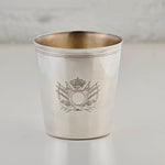 Silver cup with engraved emblem on a light gray background
