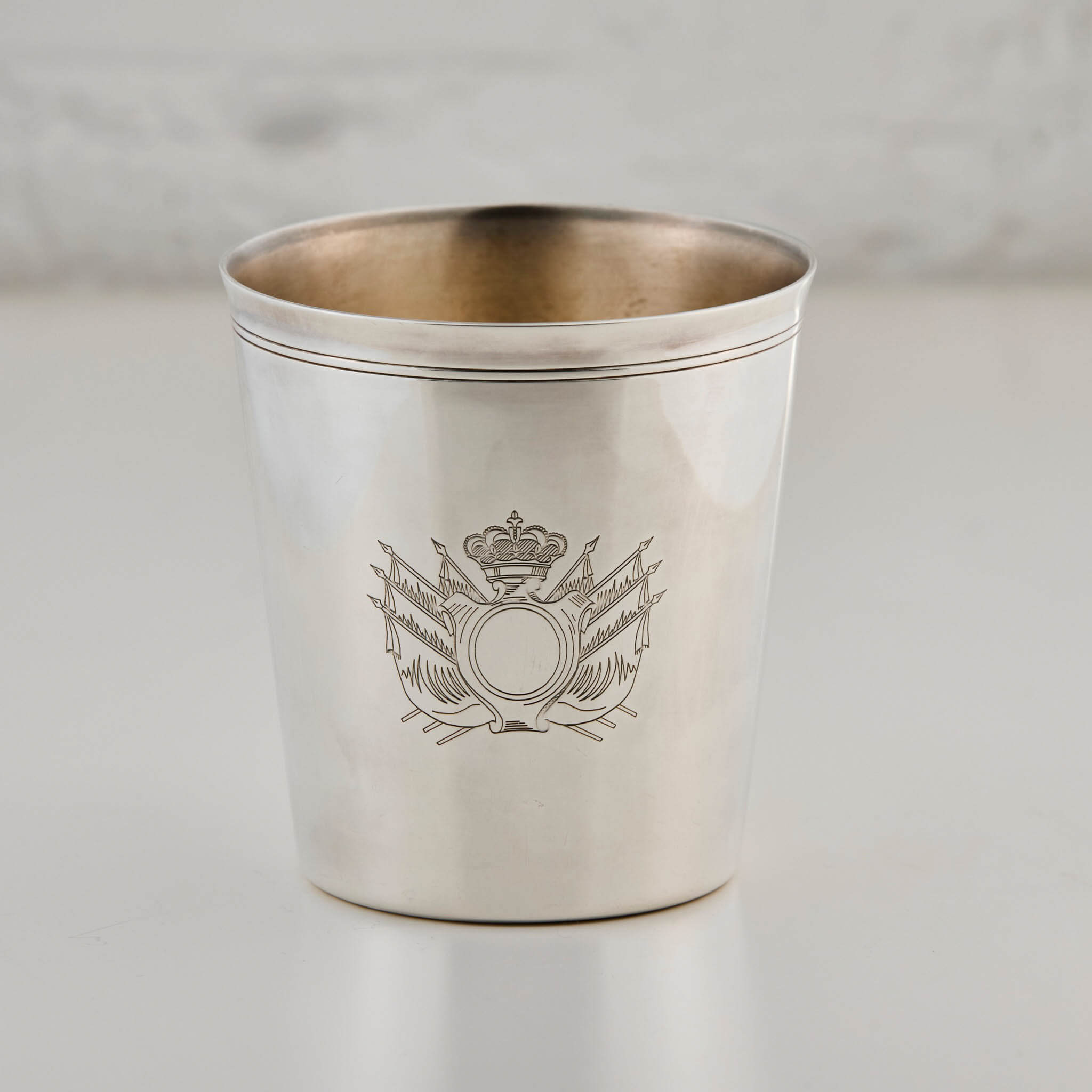 Silver cup with engraved emblem on a light gray background