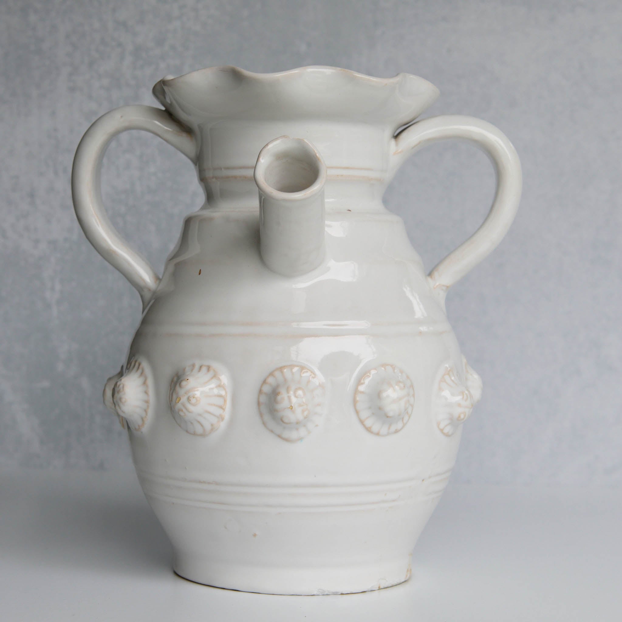 White ceramic pitcher with shell designs on a gray background