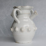 White ceramic pitcher with decorative elements on a gray background