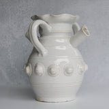 White ceramic pitcher with decorative elements on a gray background