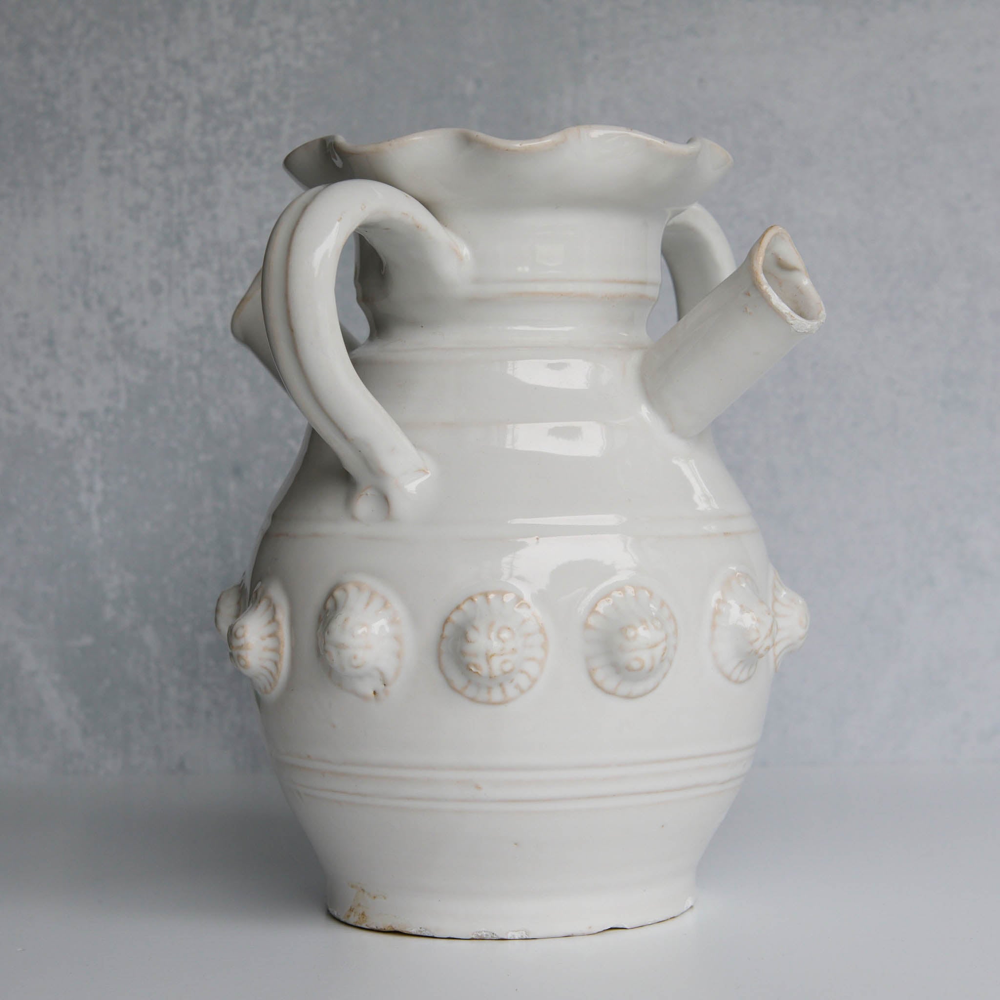 White ceramic pitcher with decorative elements on a gray background