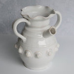 White ceramic pitcher with handles and decorative elements on a gray background