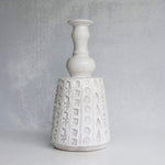 White ceramic vase with textured design on a gray background