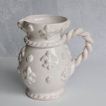 Decorative ceramic vase with floral patterns and a twisted handle on a gray background