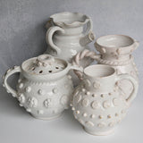 Set of white ceramic vessels with textured designs on a gray background