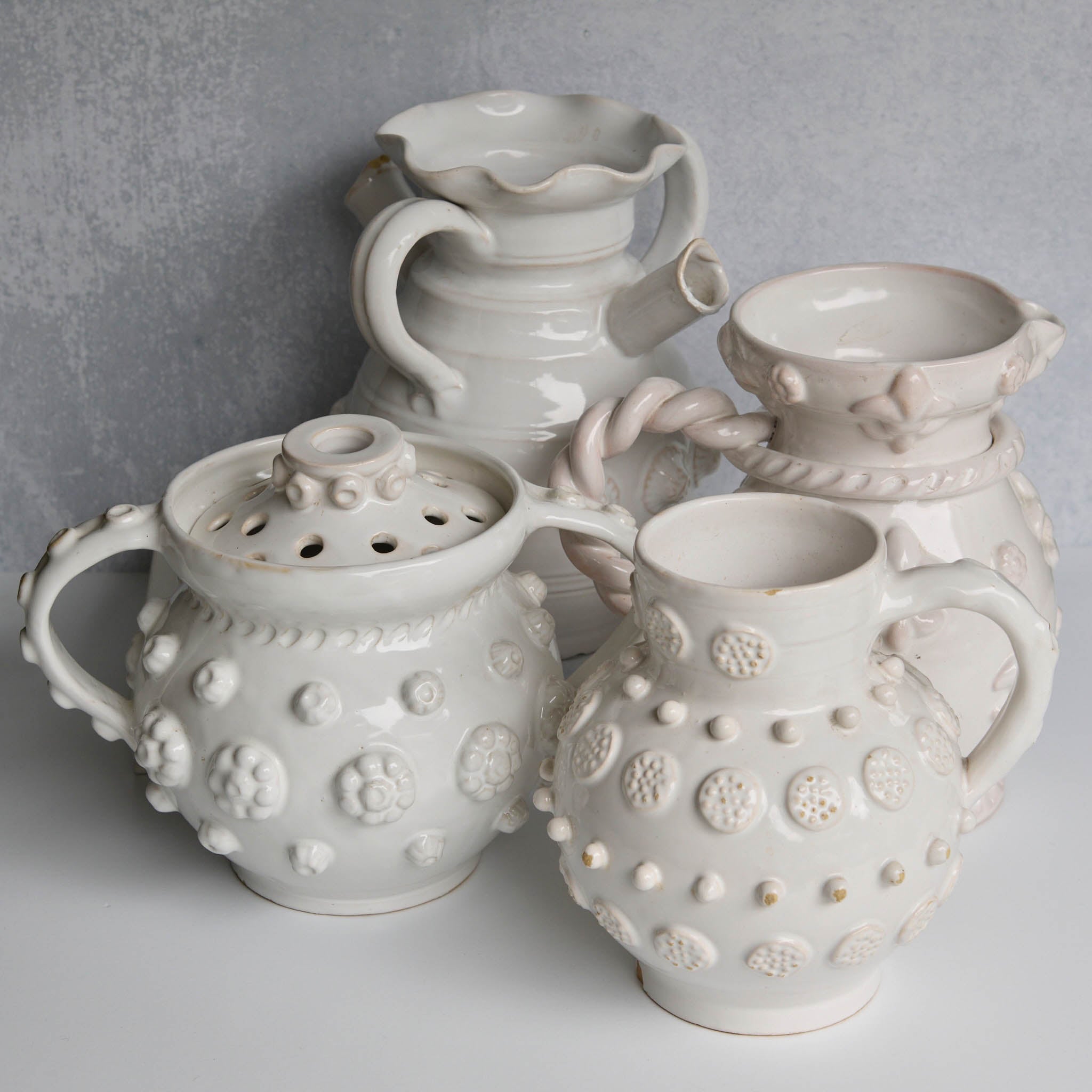 Set of white ceramic vessels with textured designs on a gray background