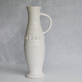White ceramic pitcher with textured design and floral patterns on a gray background