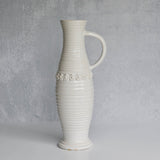 White ceramic pitcher with textured design on a gray background