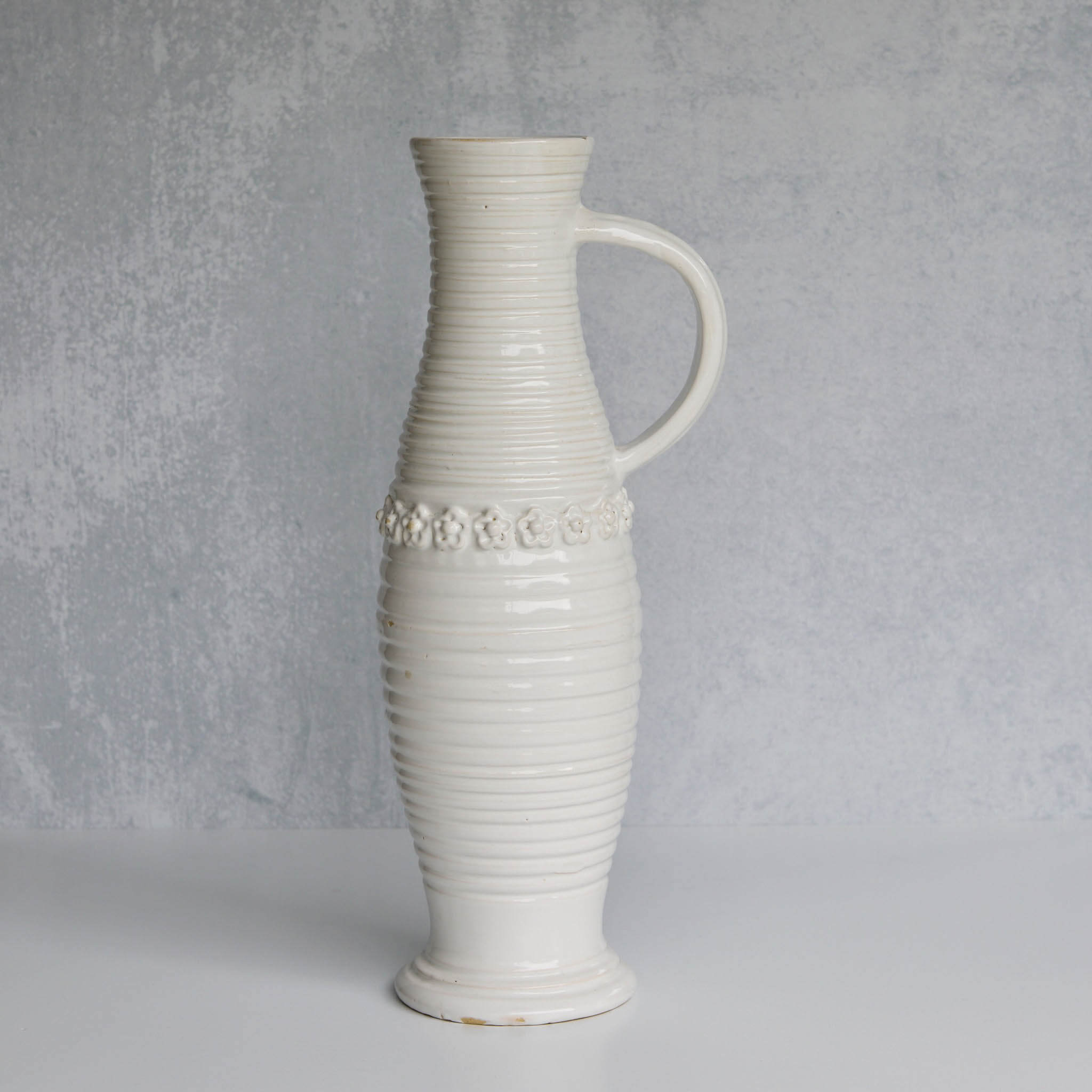 White ceramic pitcher with textured design on a gray background