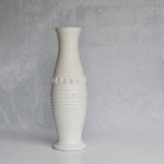 White ribbed pitcher with decorative elements on a gray background