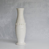 White ribbed pitcher with decorative elements on a gray background