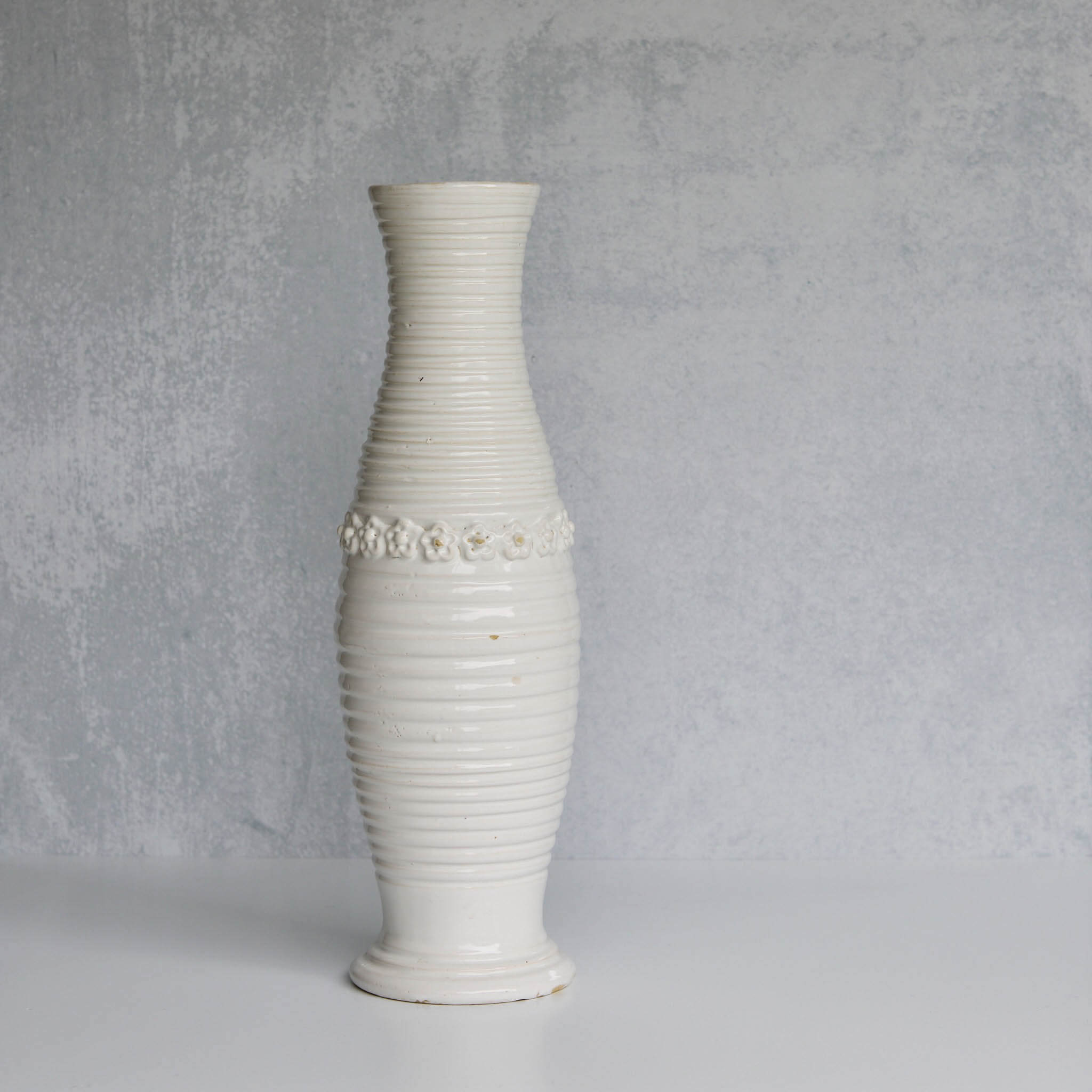 White ribbed pitcher with decorative elements on a gray background