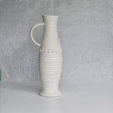 White ceramic pitcher with textured design on a gray background