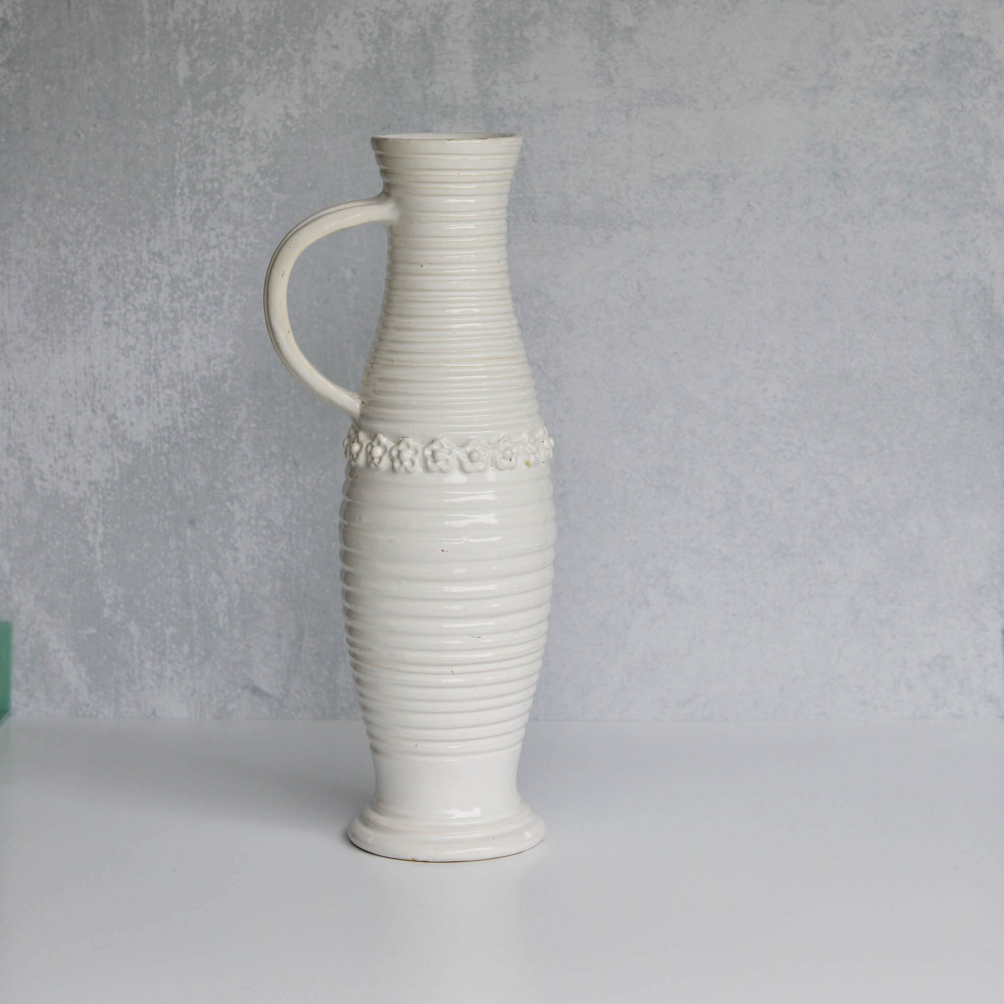 White ceramic pitcher with textured design on a gray background