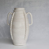 White ceramic vase with ribbed texture and handles on a gray background