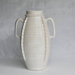 White ceramic vase with ribbed texture and handles on a gray background