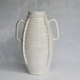 White ceramic vase with ribbed texture and handles on a gray background