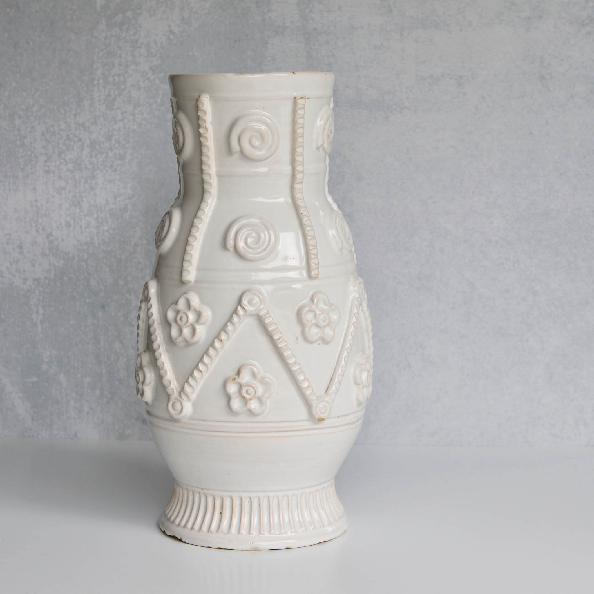 White ceramic pitcher with decorative patterns on a gray background