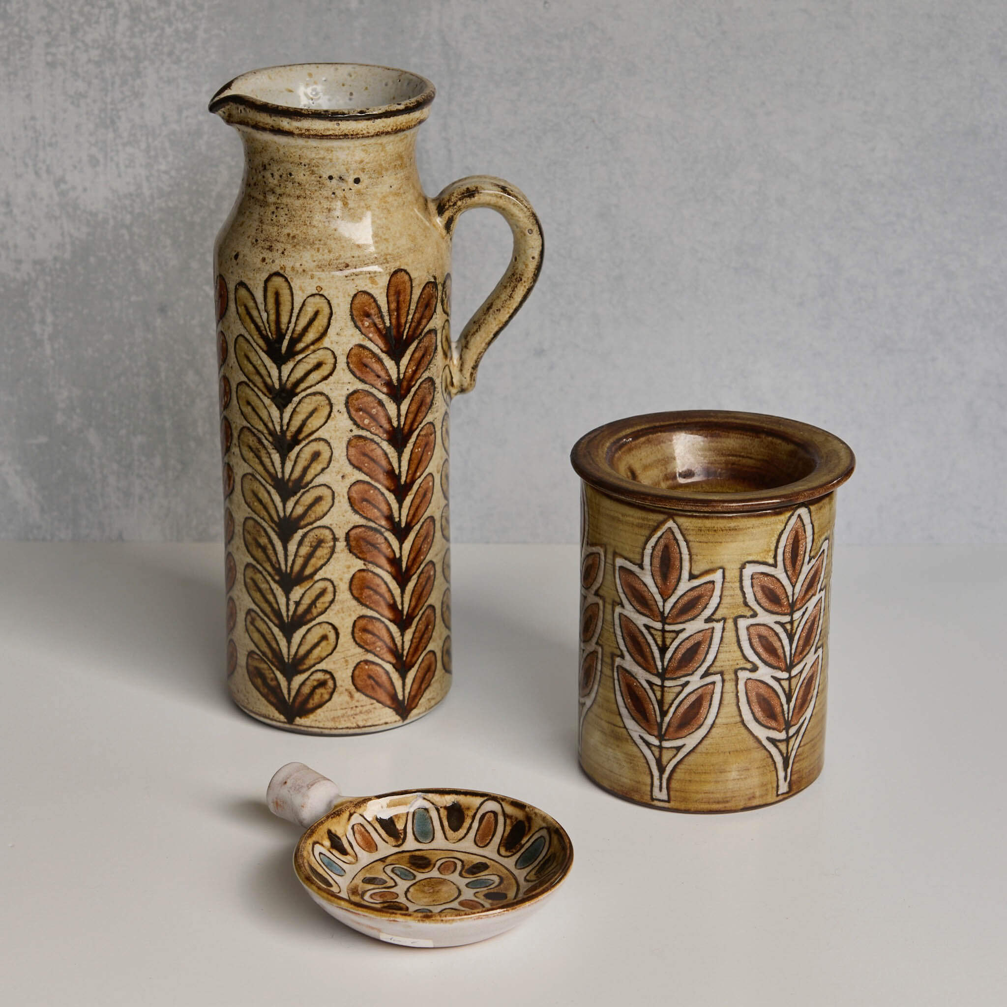 Set of ceramic Malarmey pitcher, dish, and lidded jar with leaf patterns on a neutral background