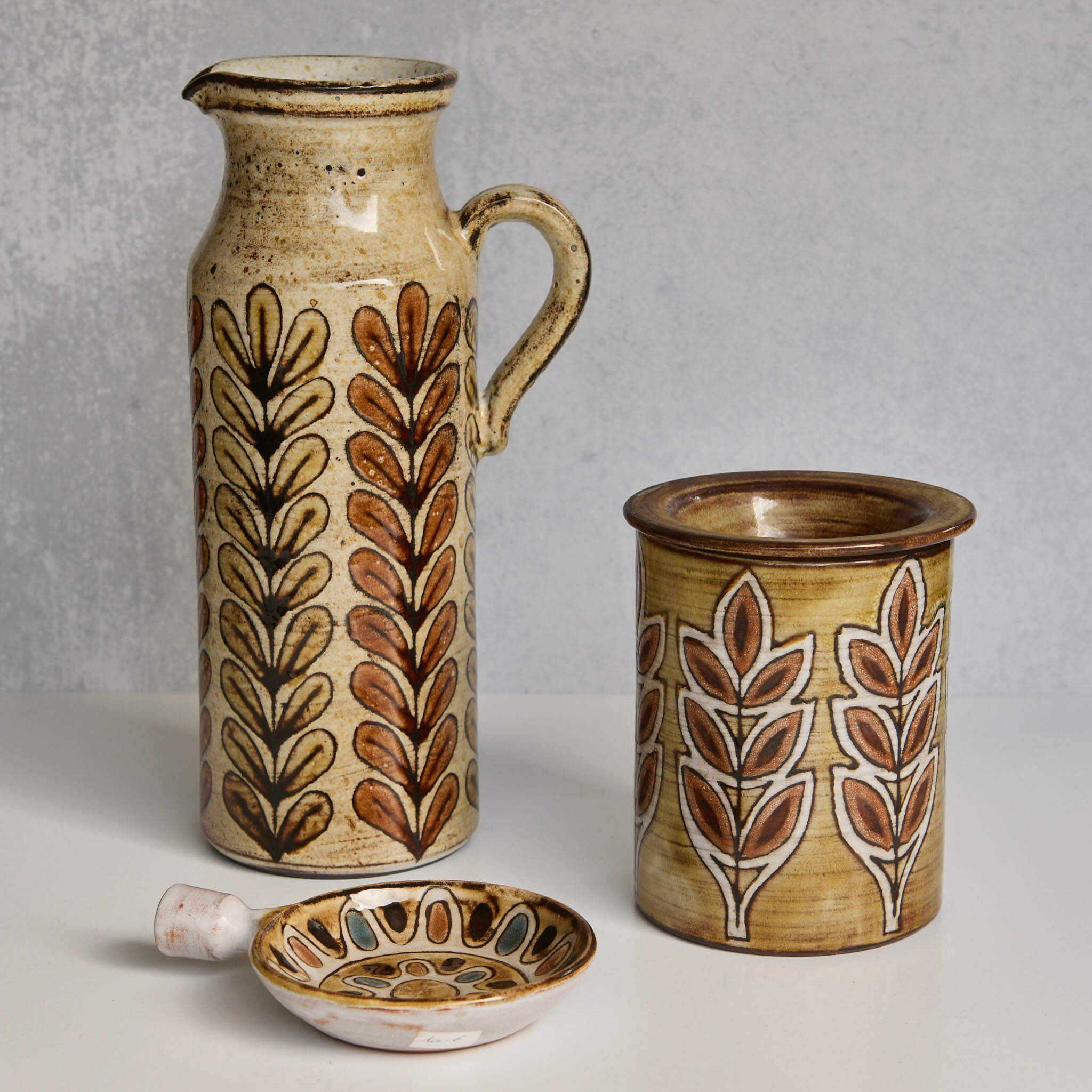 Set of ceramic Malarmey pitcher, dish, and jar with leaf patterns on a neutral background