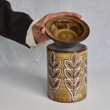 Ceramic Malarmey lidded jar with lid featuring leaf patterns, held by a hand against a neutral background