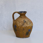 Stone pitcher with brown and blue speckled design on a white background