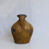 Brown stone pitcher with blue accents on a light gray background