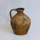 Stone pitcher with blue speckles on a white background