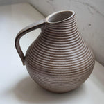 Stoneware pitcher with ribbed texture on a light background