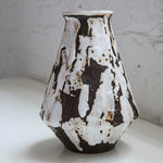 Ceramic pitcher with black and white abstract pattern on a light surface.