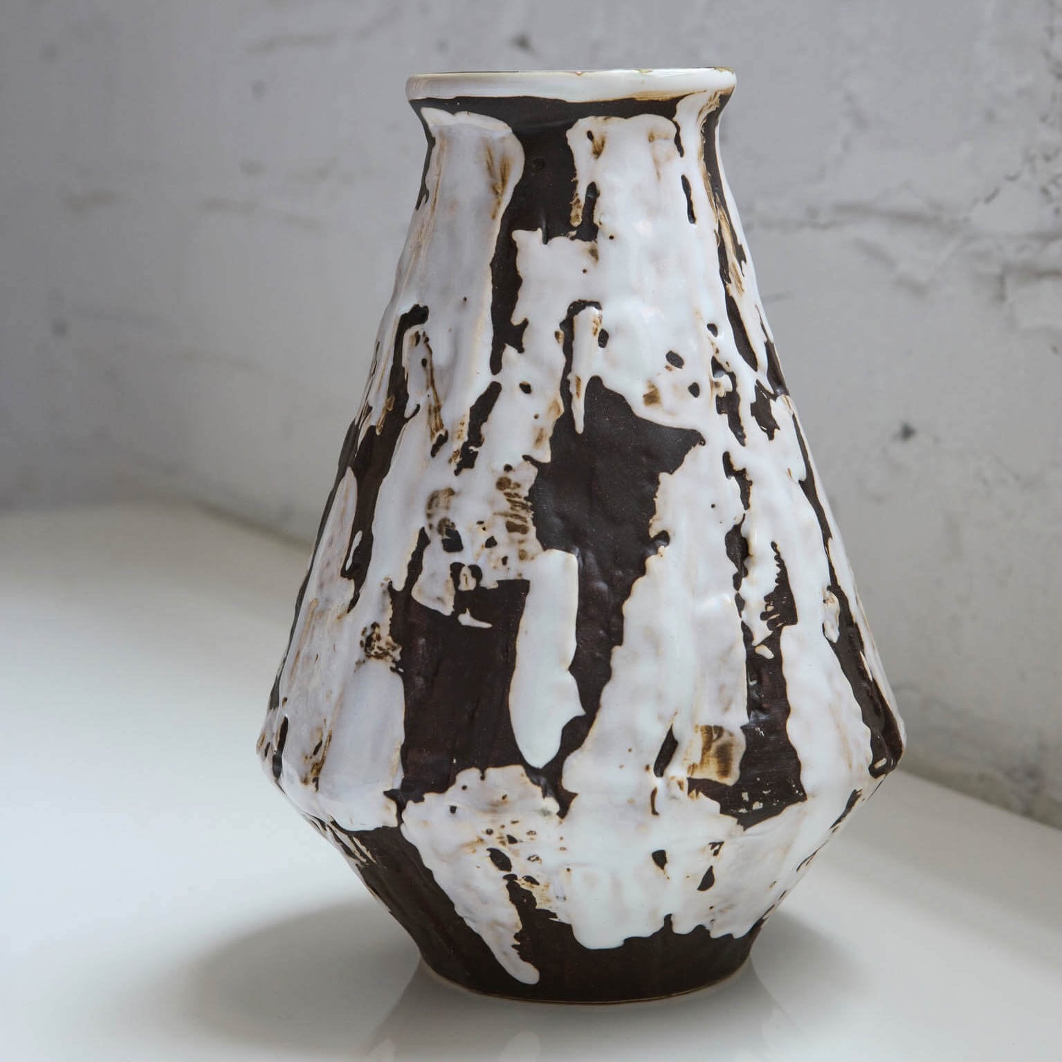 Ceramic pitcher with black and white abstract pattern on a light surface.