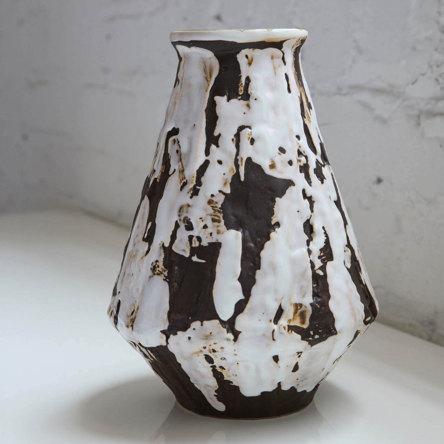 Ceramic pitcher with black and white abstract pattern on a light surface.