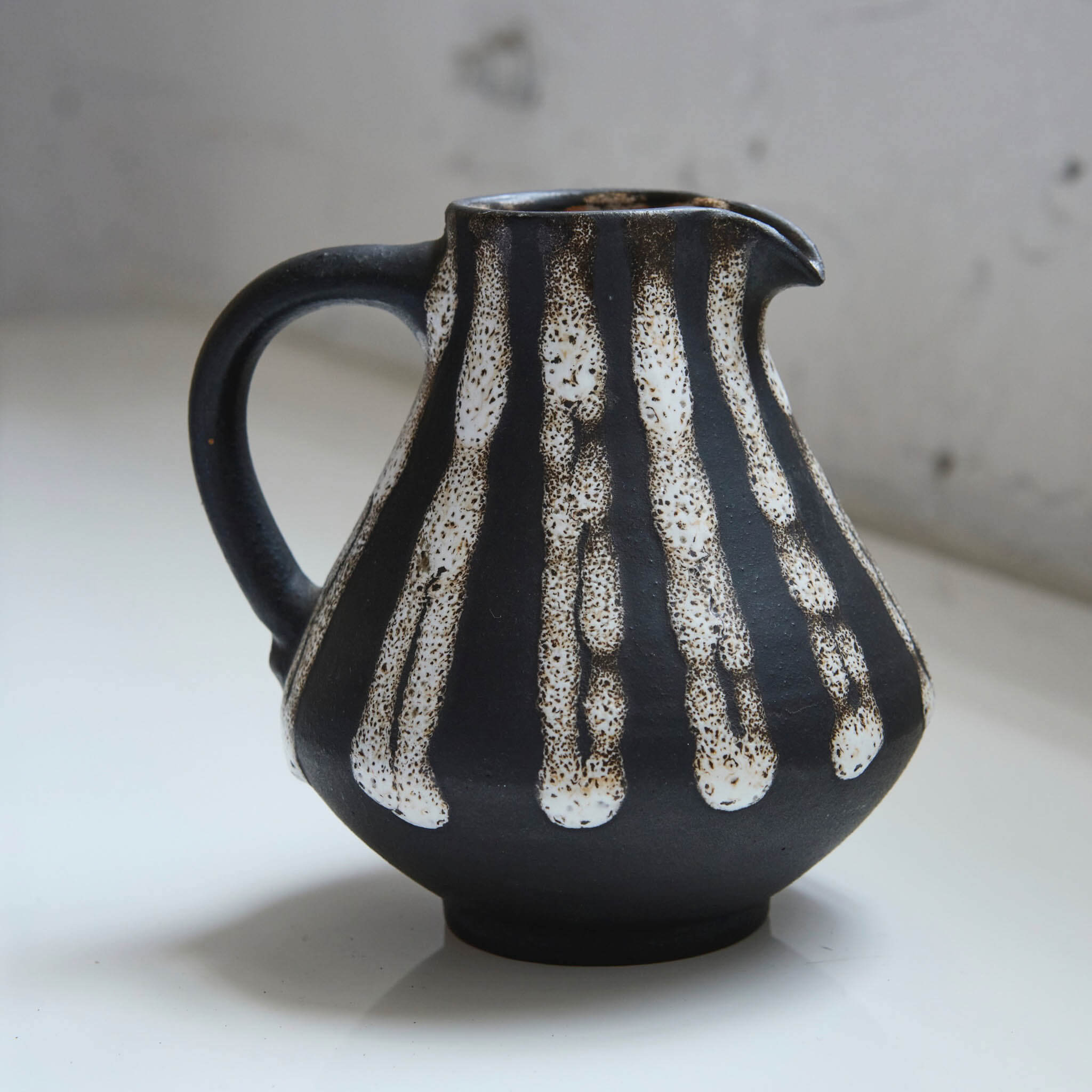 Black ceramic pitcher with white abstract patterns on a light background