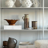 Decorative shelves with various ceramic vases and bowls against a neutral background