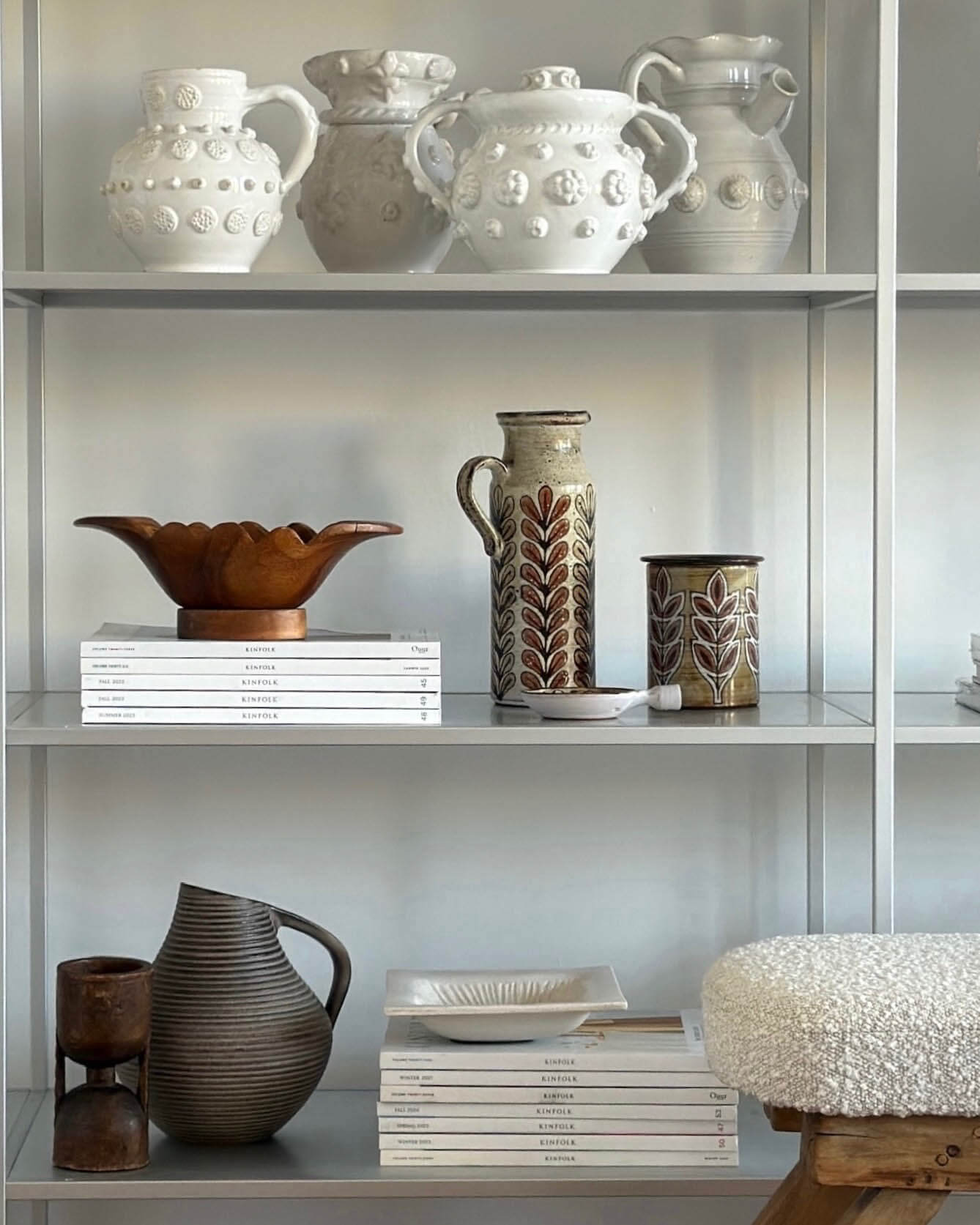 Decorative shelves with various ceramic vases and bowls against a neutral background