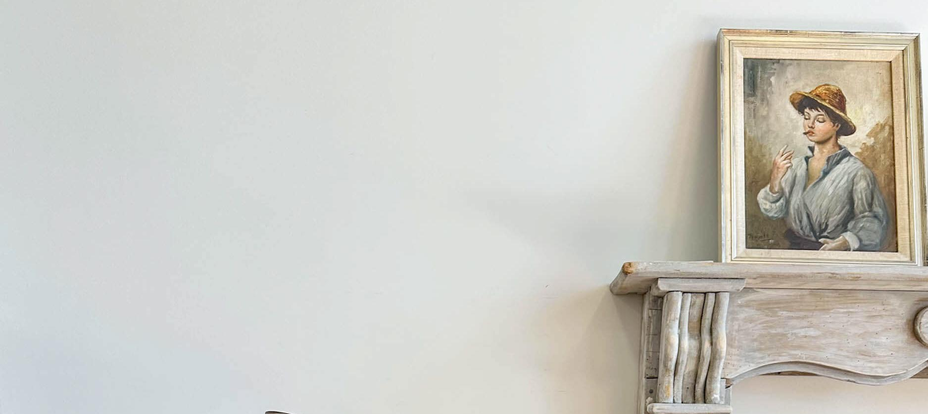 Framed portrait of a woman on a wooden mantle against a white wall